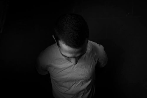 Free High angle black and white portrait of a man looking down, creating a dramatic visual effect. Stock Photo