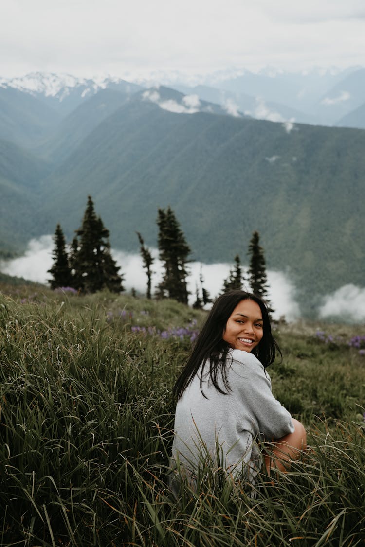 Young Ethnic Woman Sitting On Hill Slope