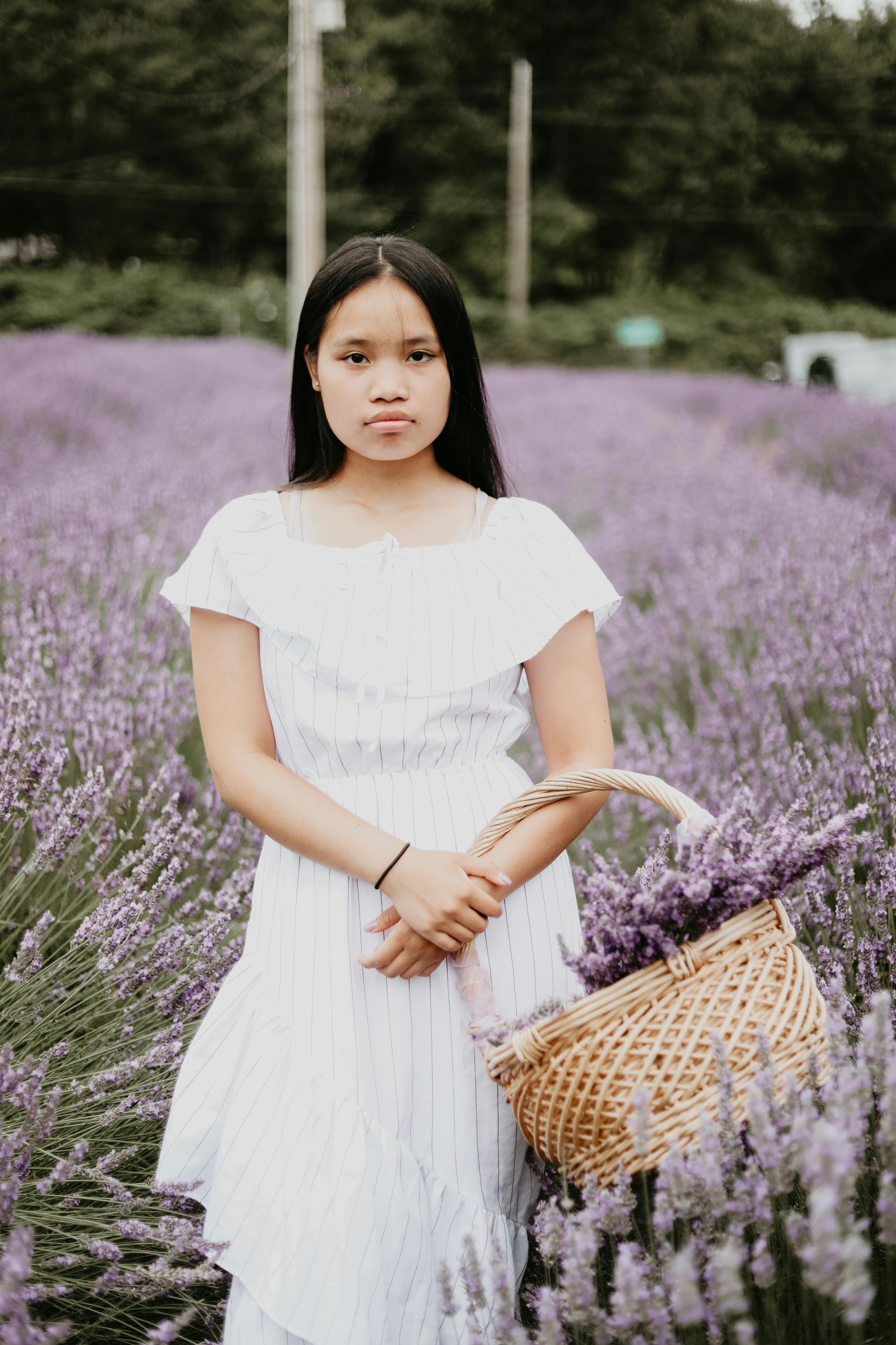 一名年轻女子提着篮子，站在充满活力的薰衣草田里，营造出宁静的夏日氛围