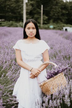 一名年轻女子提着篮子，站在充满活力的薰衣草田里，营造出宁静的夏日氛围