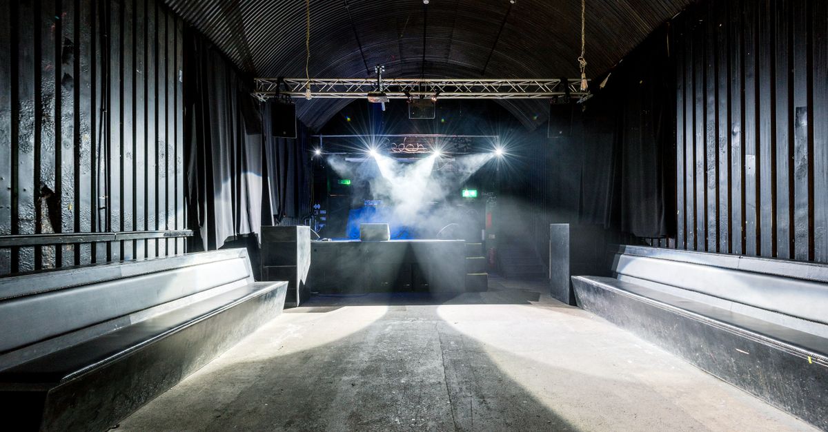 A deserted nightclub featuring stage lighting and seating, highlighting its industrial design.