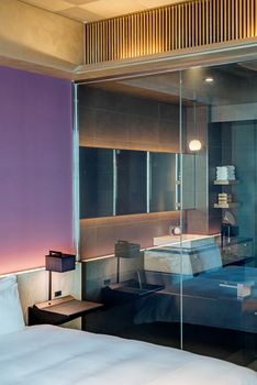 A sleek and modern bedroom interior featuring a glass divider and elegant design elements.