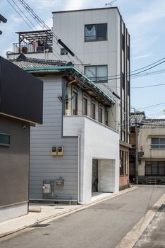 京都一条宁静的狭窄街道上，现代与传统建筑在晴朗的天空下交相辉映