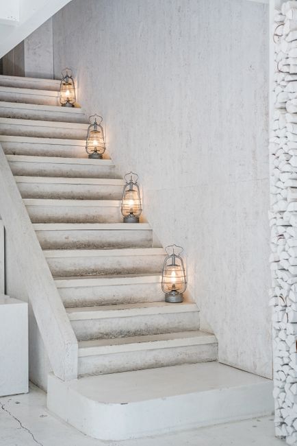 Minimalist white staircase with vintage lanterns creating a warm ambiance.