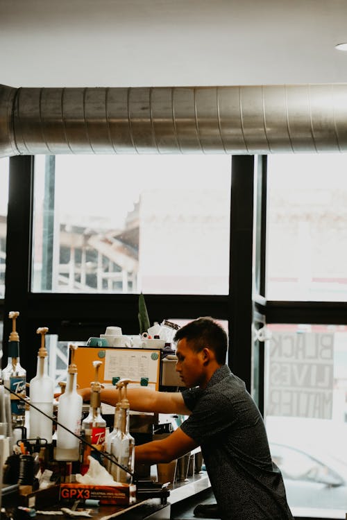 Focused ethnic barista preparing drink at counter