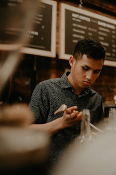 Focused barista preparing a beverage in a warm, modern café setting.