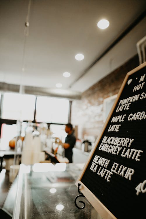 Free Blurred barista at modern cafeteria counter with menu board Stock Photo