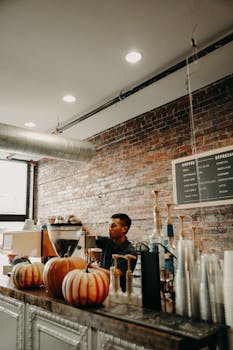 Focused young ethnic male barista preparing beverage while working at counter in modern cafe