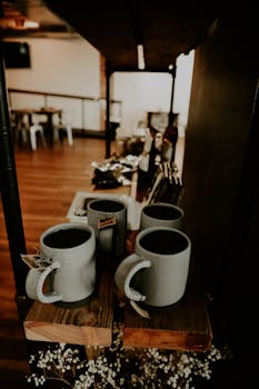 A cozy indoor café scene showcasing ceramic mugs on a rustic wooden shelf.