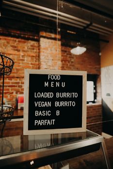 Black square menu board placed on glass window case in contemporary coffee shop