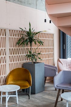 Bright interior of a cozy coffee shop featuring modern chairs, a plant, and stylish design elements.