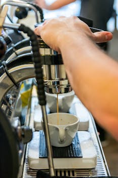 Barista preparing espresso with a commercial espresso machine in a cafe environment.