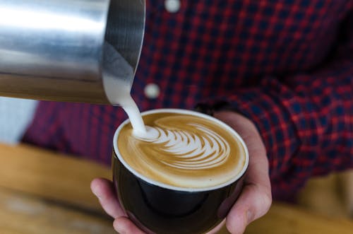 Free Close-Up Shot of a Person Pouring Latte on a Cup of Coffee Stock Photo