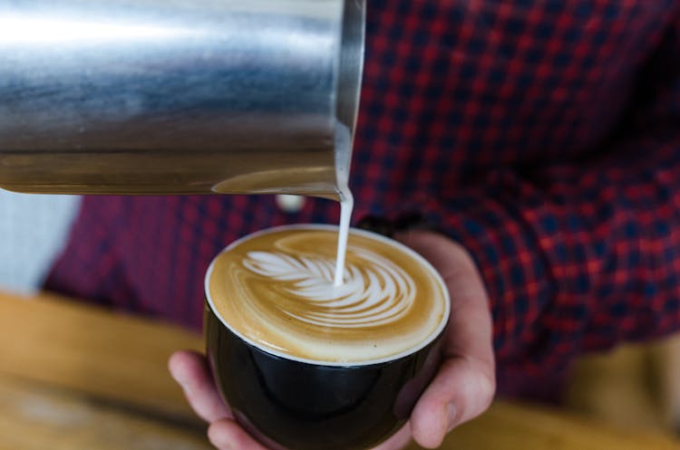 Close-Up Shot Of A Person Pouring Latte On A Cup Of Coffee