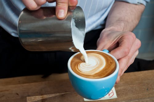 Free Close-Up Shot of a Person Pouring Latte on a Cup of Coffee Stock Photo