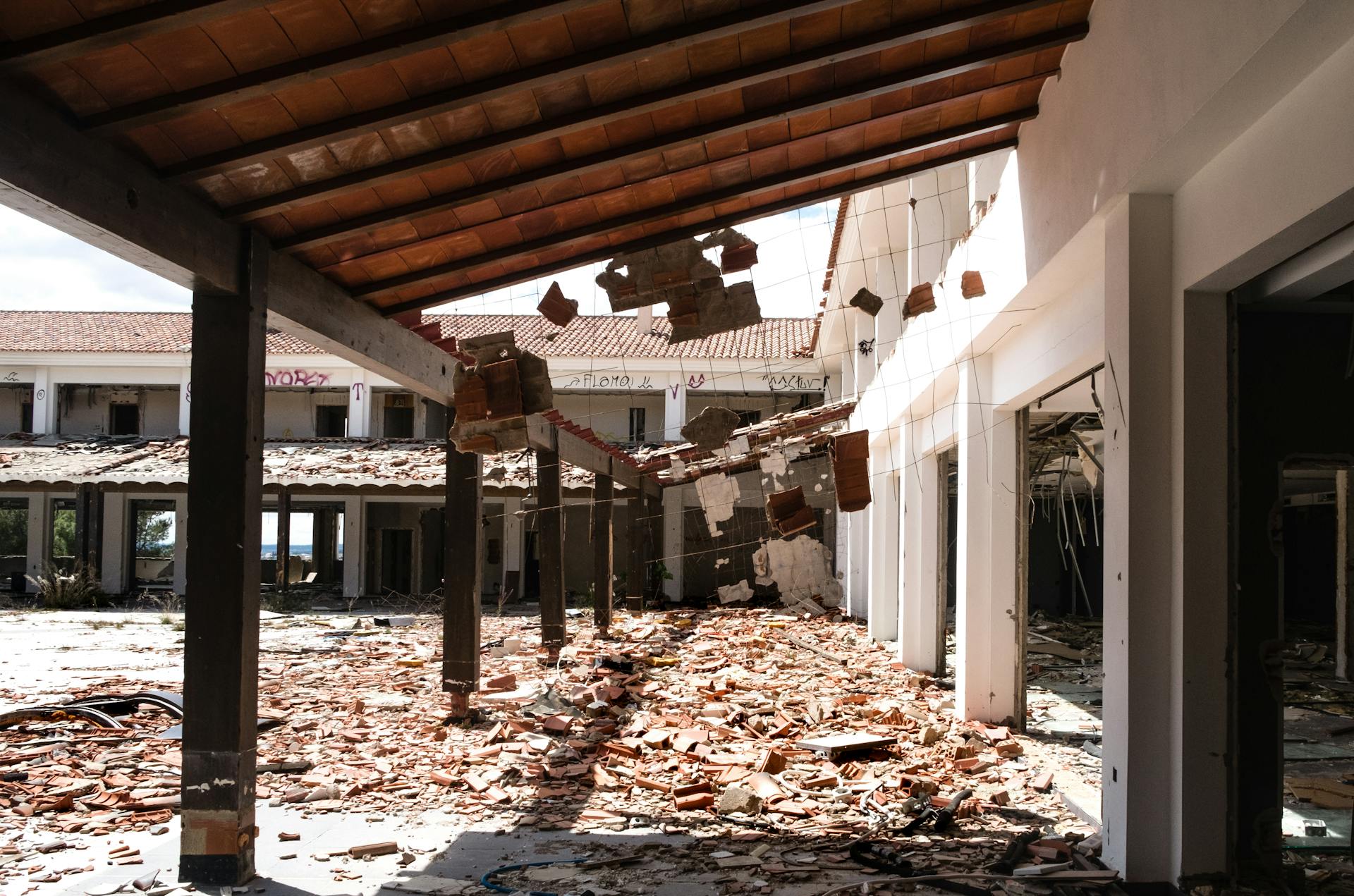 A ruined building with debris and fallen roof in an abandoned site, showcasing destruction.