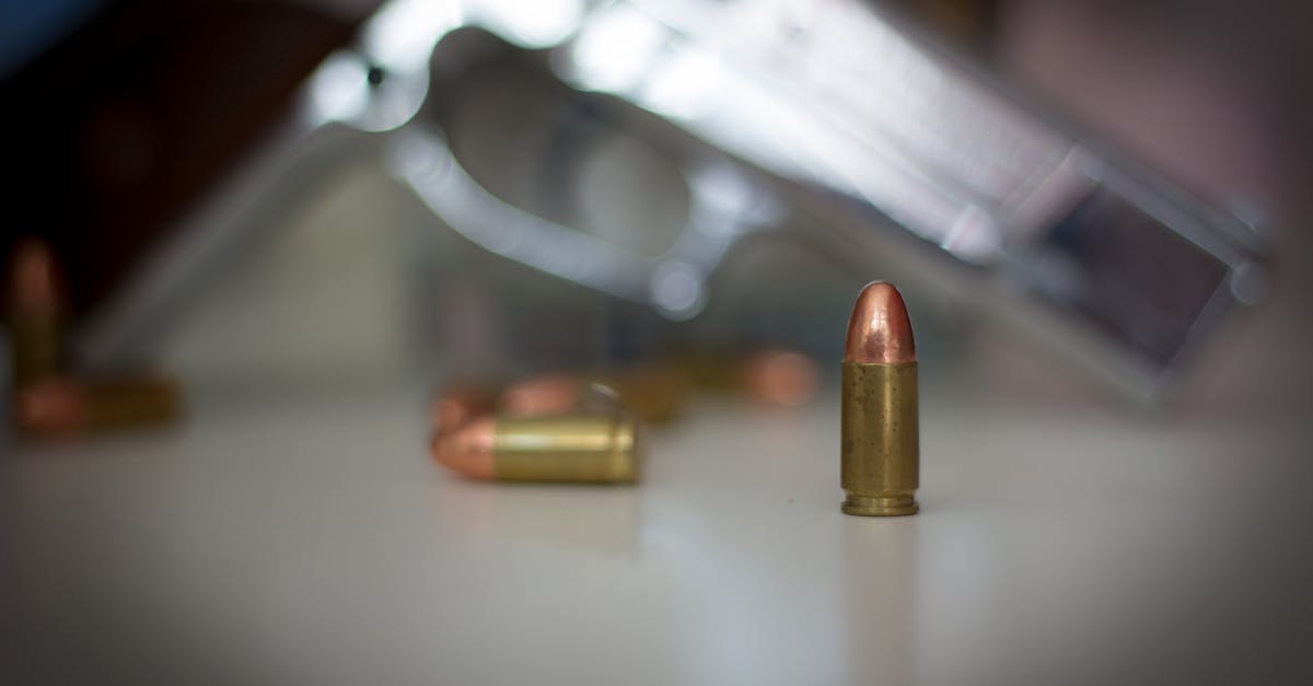 Photo by Enrico Hänel Focus on a bullet with a blurred pistol in the background, highlighting firearm accessories.