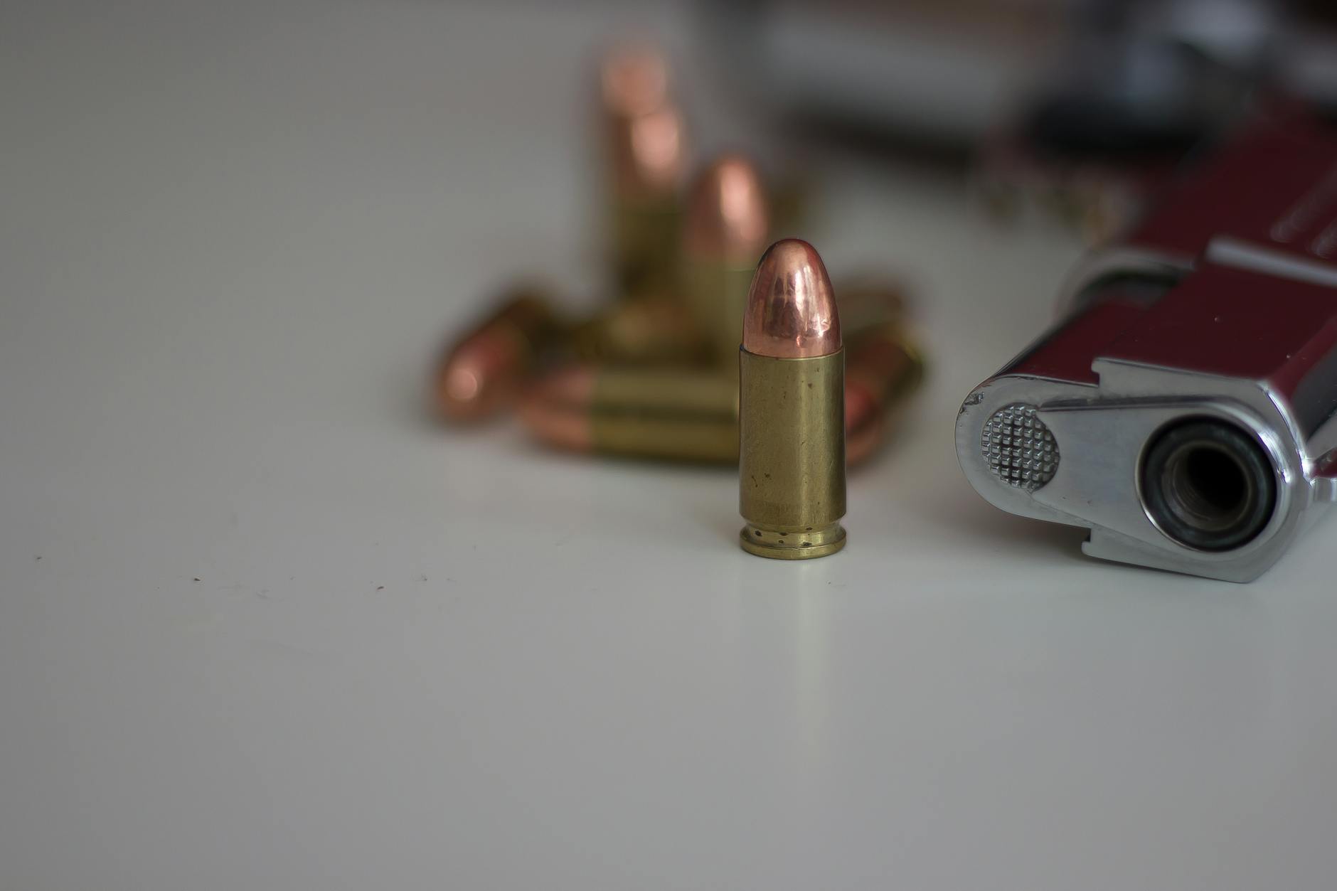 A detailed image of a handgun and multiple bullets on a white background, showing focus on firearm elements.