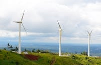 White Wind Turbine on Green Grass Field Near Body of Water
