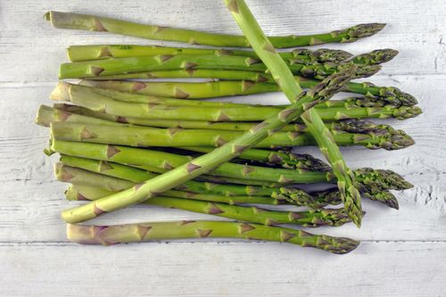 Free A vibrant bunch of green asparagus spears laid out on a white wooden surface, showcasing fresh produce. Stock Photo