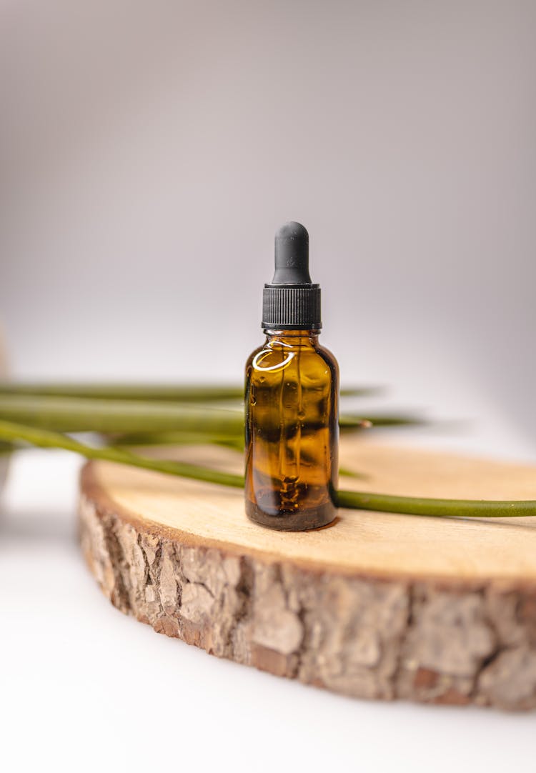 Brown Glass Bottle For Essential Oil On Decorative Wooden Board