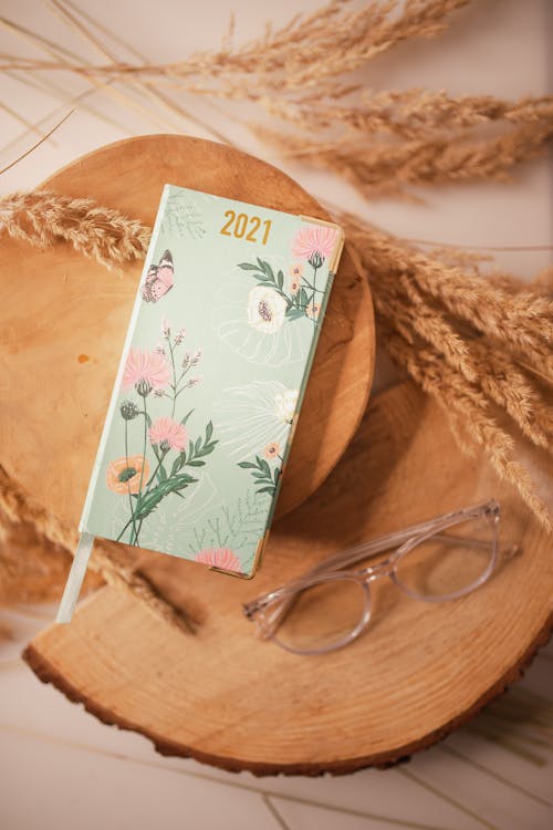 Free Top view composition of ladies 2021 year diary and eyeglasses arranged on decorative wooden boards near cereal spikes Stock Photo
