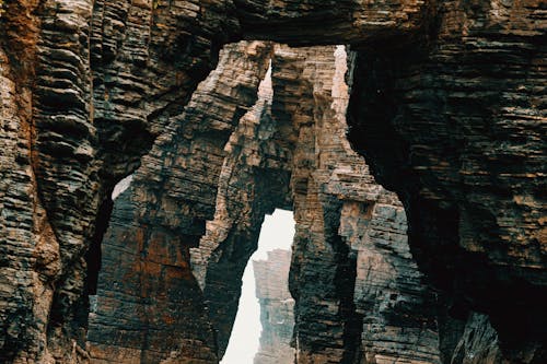 Tall majestic brown bare cliffs with rough uneven surface in canyon in daytime