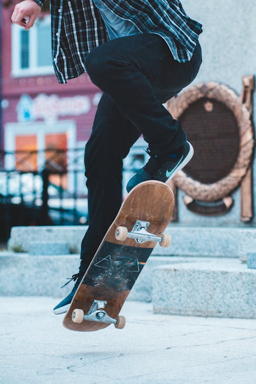 Crop man jumping on skateboard