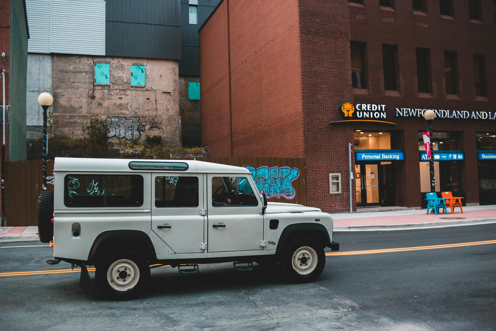 White offroad vehicle parked on a city street near a credit union in Toronto. Urban and vibrant.