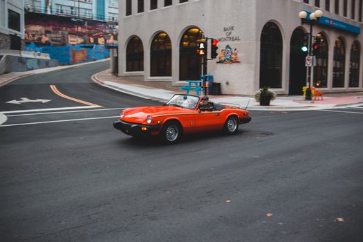 Anonymous couple in bright luxury vintage auto driving on asphalt roadway near urban buildings during trip