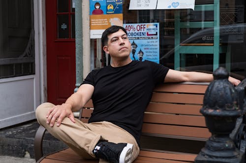 Mn in Black Shirt and Brown Pants Sitting on Bench 