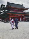 People Wearing Traditional Kimonos Walking Near a Red and Black Temple