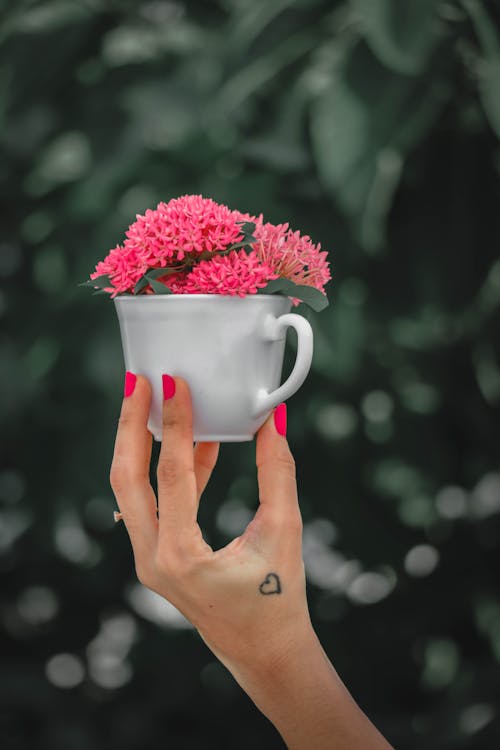 Femme Méconnaissable Présentant Une Tasse Avec Des Fleurs Fraîches