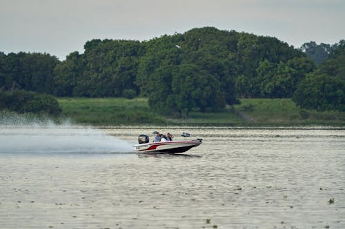 People Riding a White and Red Speed Boat on a River