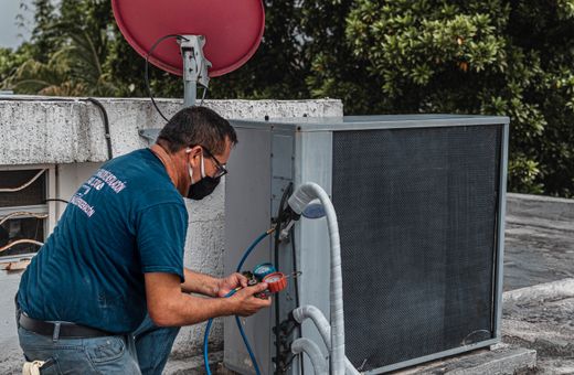 Technician servicing an outdoor air conditioner with a manifold gauge