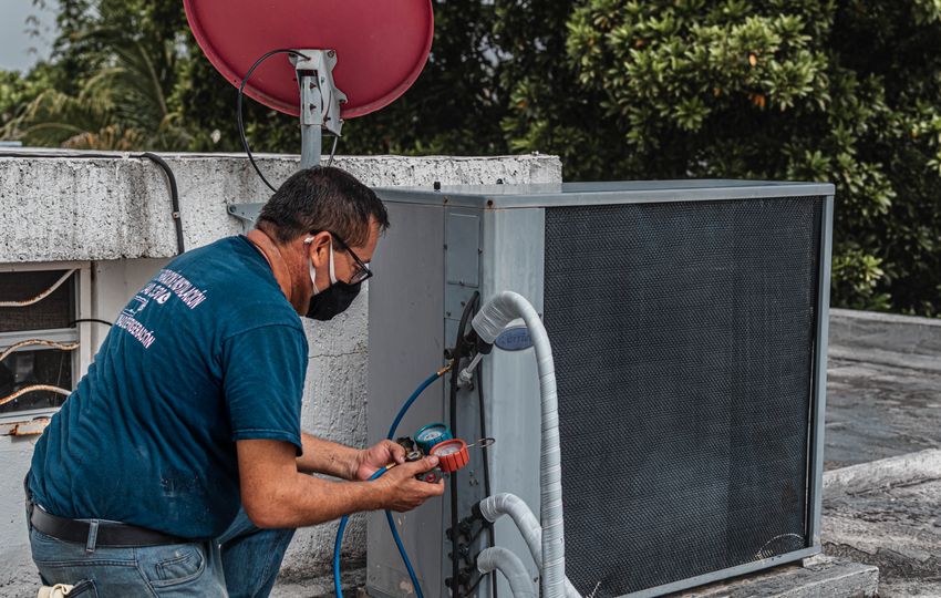 Technician servicing air-conditioning refrigerant system — representative real photograph, not an ESPC project