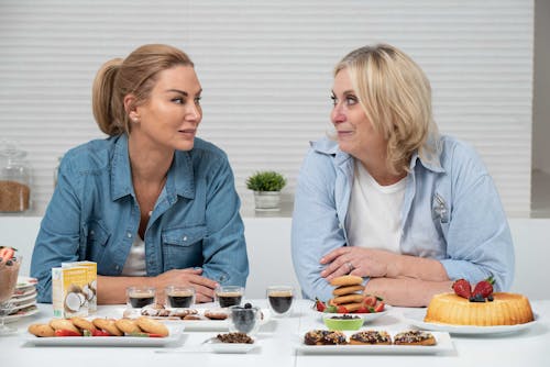 Free Women at a Table with Assorted Delicious Sweets and Cups of Black Coffee Stock Photo