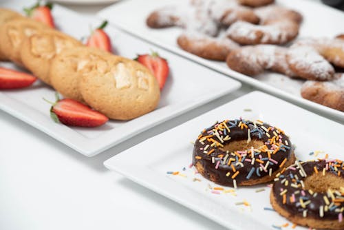 Free Chocolate Doughnuts with Sprinkles on a Plate Beside Cookies with Strawberries Stock Photo
