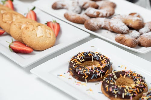 Free Chocolate Doughnuts with Sprinkles on a Plate Beside Cookies with Strawberries
 Stock Photo