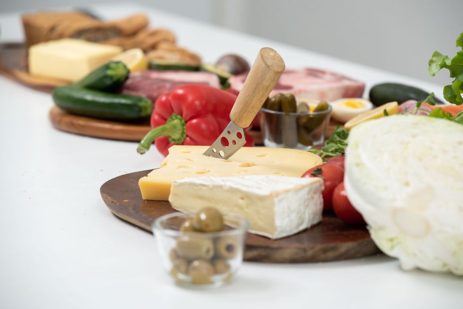 A delicious assortment of cheeses, olives, and fresh vegetables on a wooden platter.