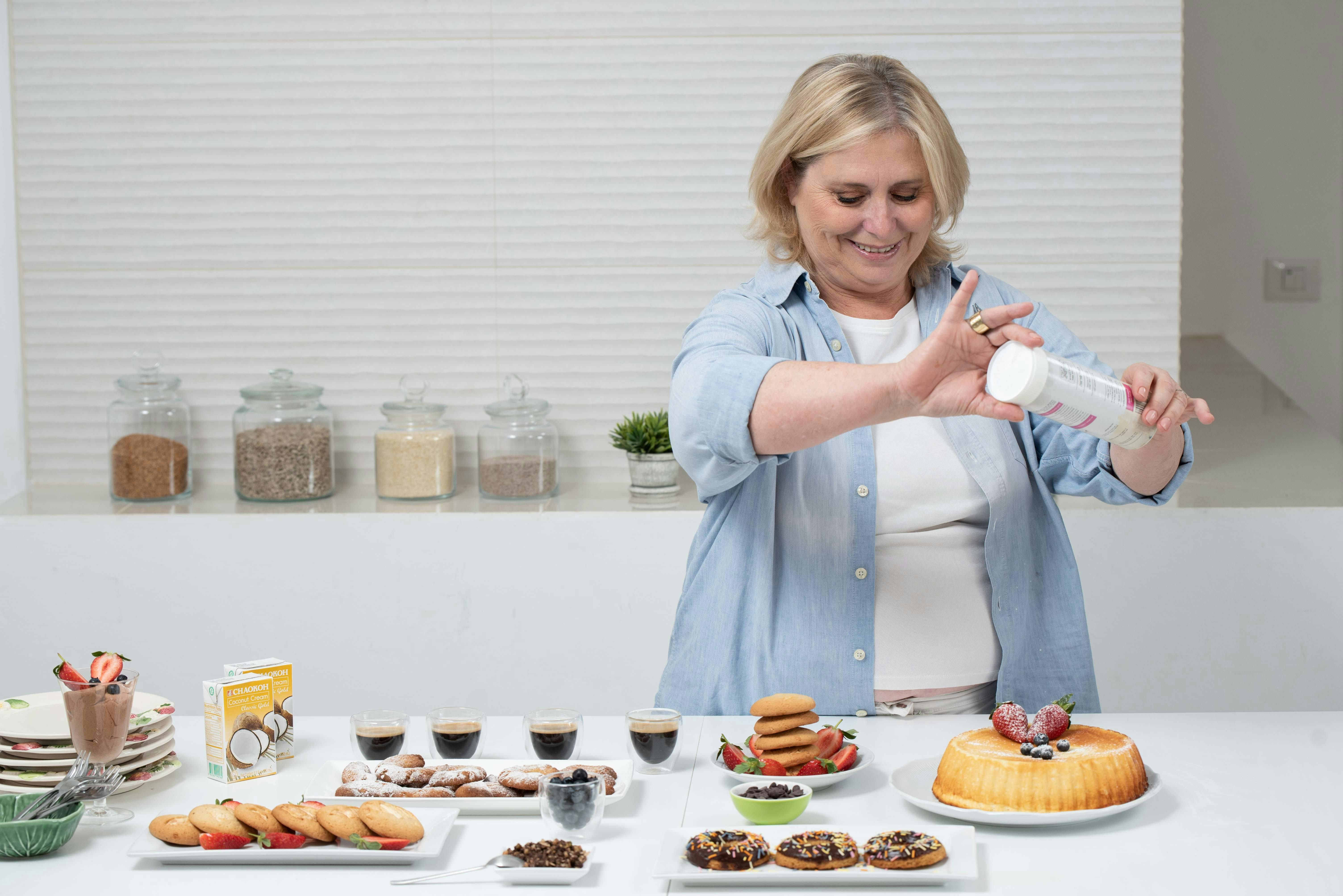 Smiling home baker decorating a cake in her kitchen