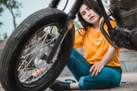 Woman in Yellow Shirt and Blue Denim Jeans Sitting on Black Motorcycle Wheel