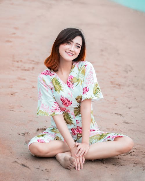 Woman in Floral Dress Sitting on Brown Sand 