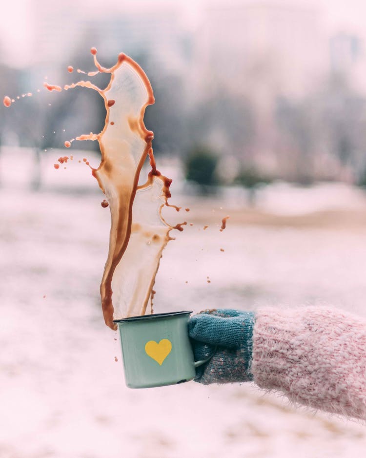 A Hand Wearing Winter Holding A Cup Of Spilled Hot Coffee