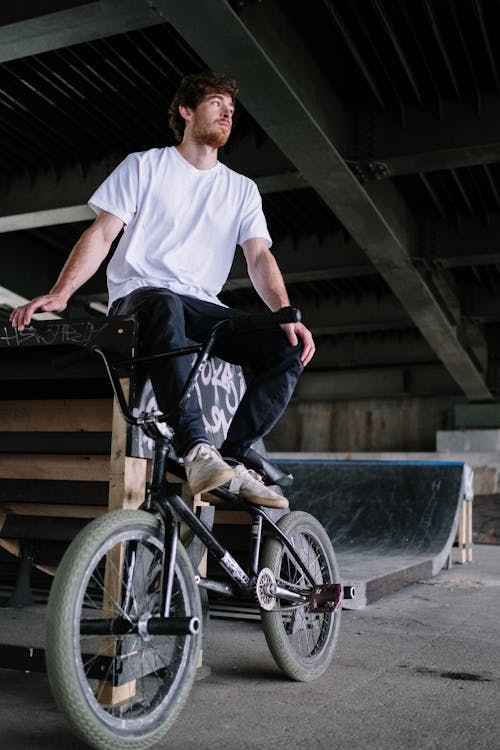 Man in White T-shirt Sitting Beside a Bike