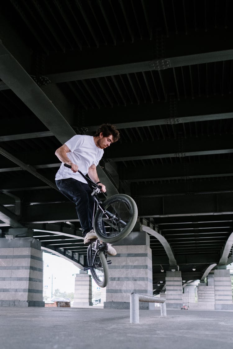 Man Doing Bike Trick Under A Bridge