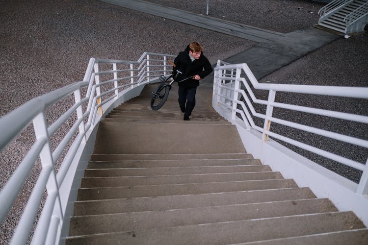 Man Carrying A Bike Up The Stairs