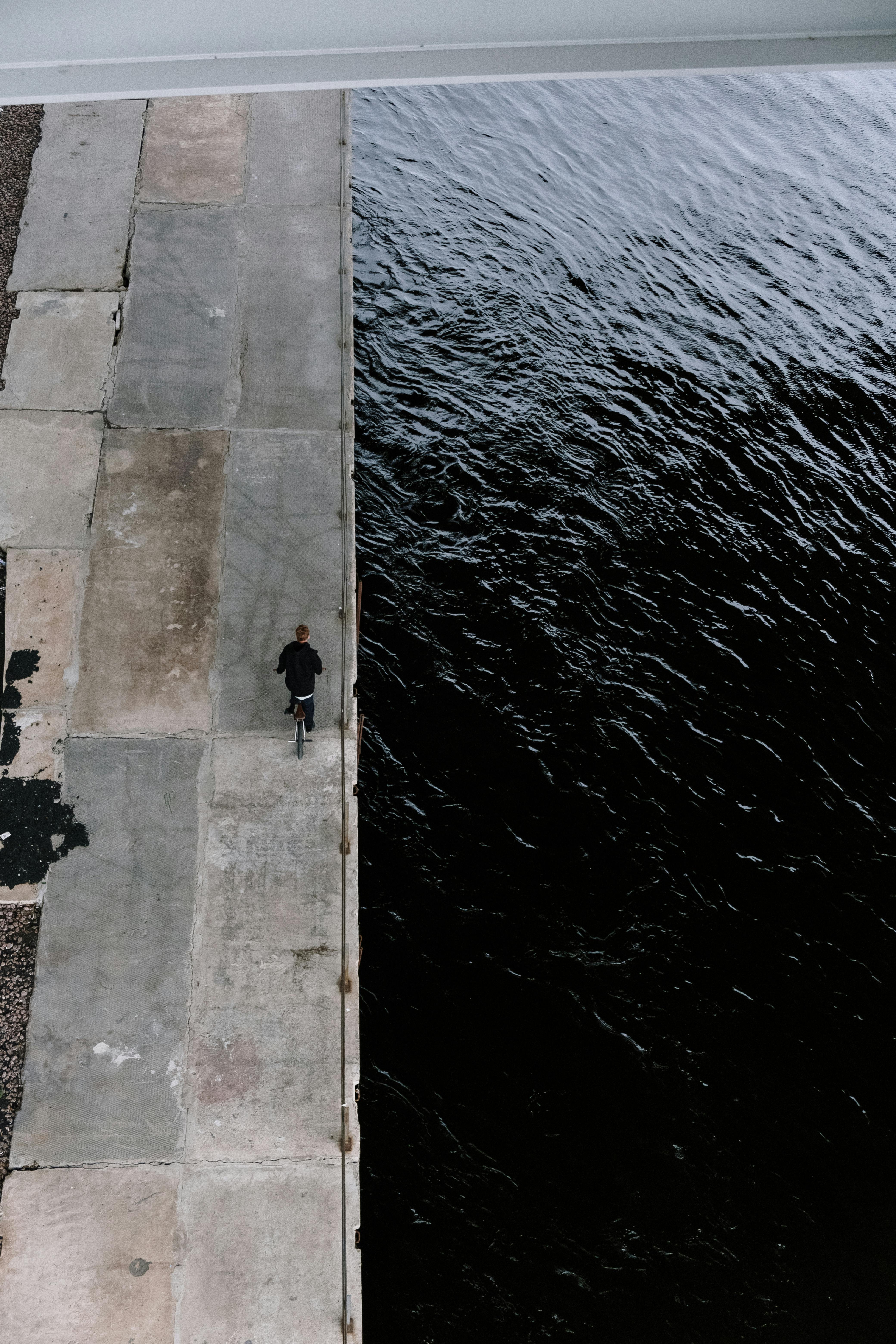 从空中视角拍摄的河边小径上，一个孤独的人物正在行走