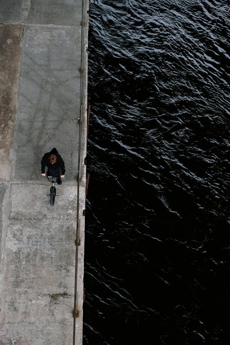 Person In Black Jacket Biking Near The Lake