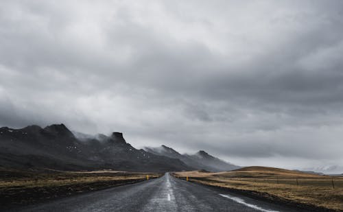 Road near the Mountains Under Cloudy Sky